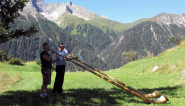 Alphorn duet in the Swiss mountains, Piz Mitgel, Canton Graubunden, in the background